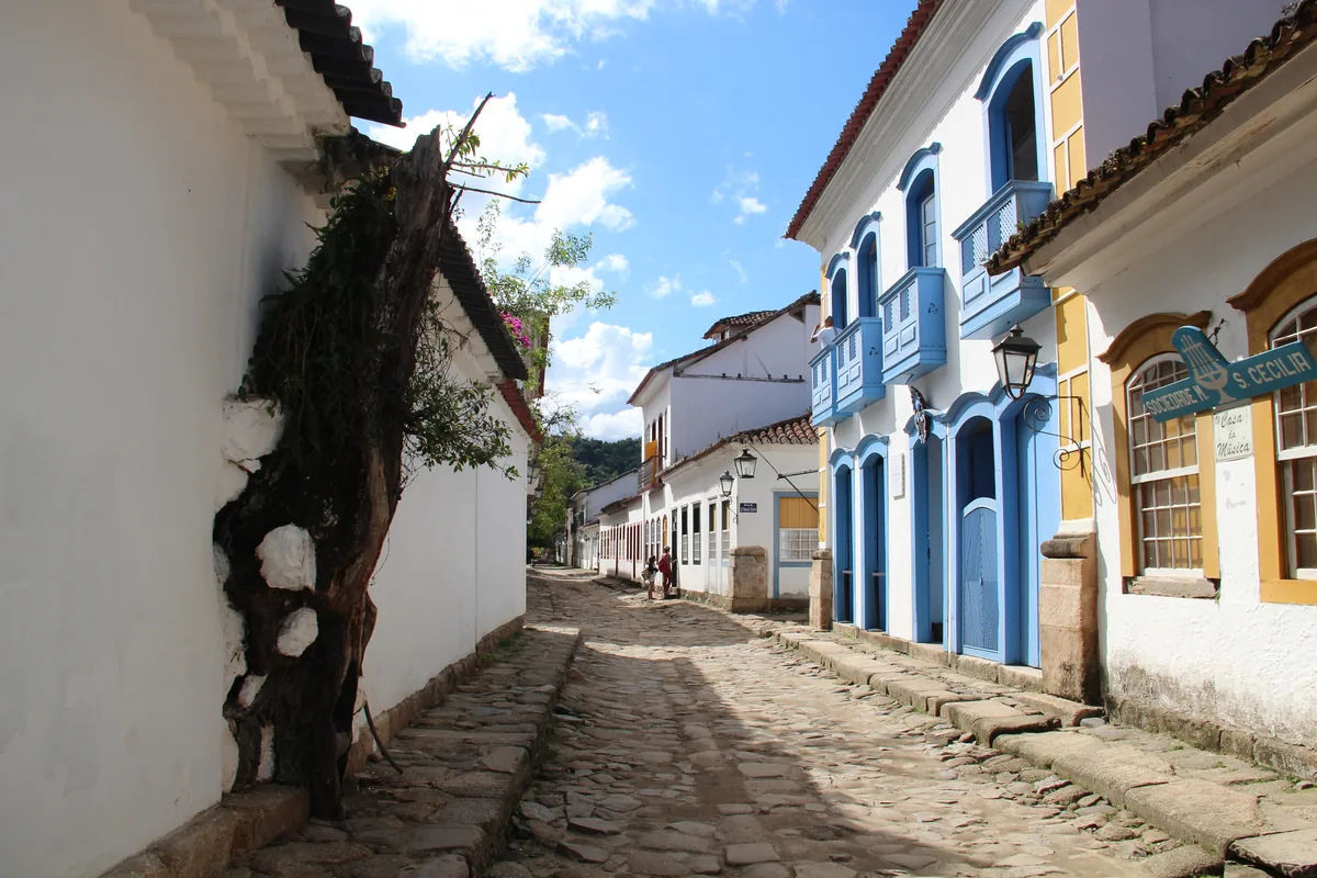 Rua de pedra do centro histórico de Paraty, com casarões coloniais brancos e janelas coloridas
