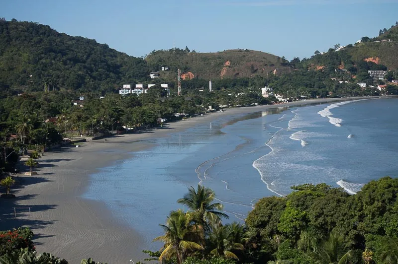 Vista panorâmica da Praia da Enseada em Ubatuba, com a longa faixa de areia, mar calmo e os morros da Serra do Mar ao fundo