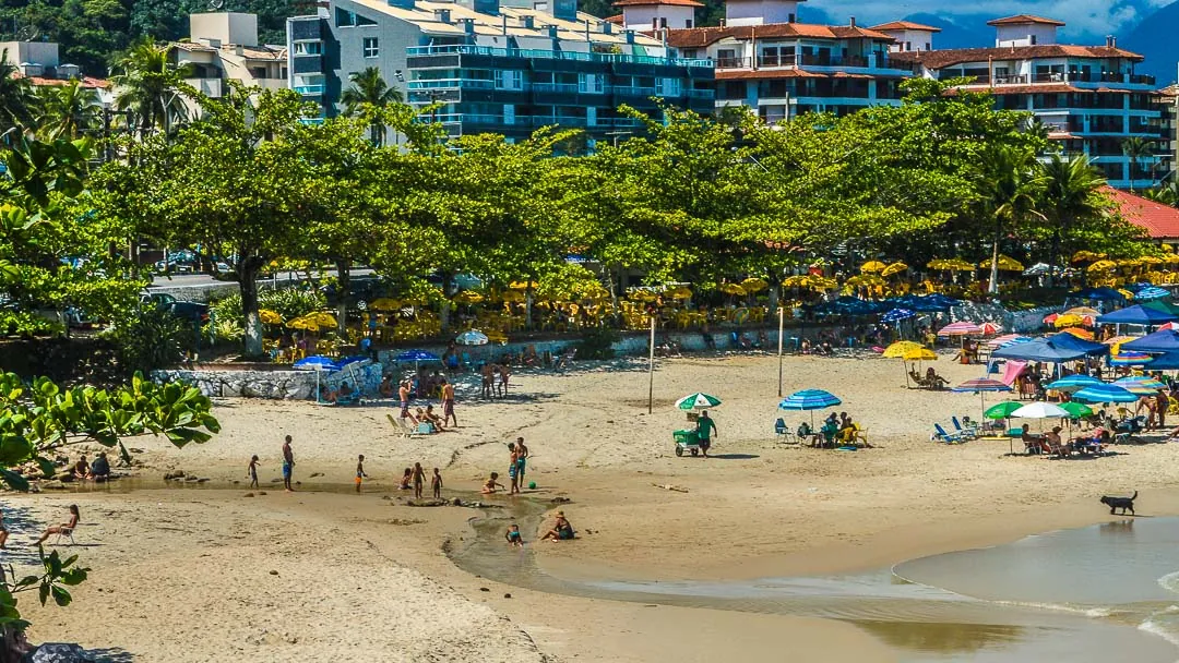 Praia Grande em Ubatuba com faixa de areia, guarda-sóis coloridos e banhistas em dia de sol